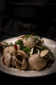 A vibrant plate of Qingdao-style grilled clams garnished with fresh herbs.