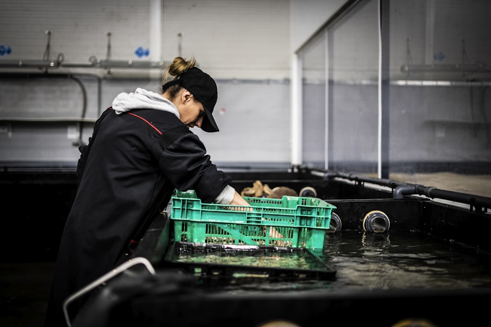 a woman in a black jacket and a green crate