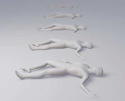 Several identical human figures are positioned in a line, lying down on a smooth, gradient surface that transitions from light gray to white. They appear to be sculptural or mannequin-like, with each figure slightly smaller and more distant than the previous one.