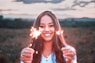 a woman holding two sparklers in front of her face