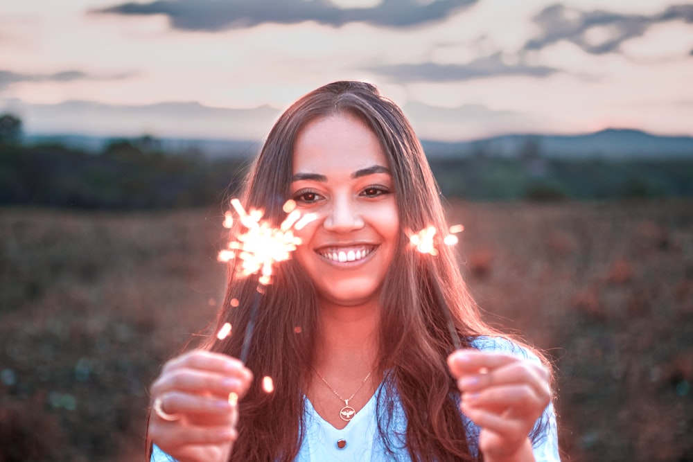 a woman holding two sparklers in front of her face
