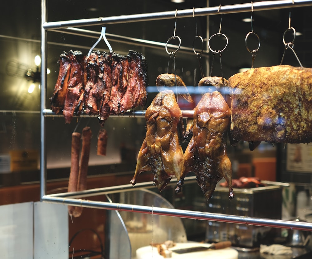 a bunch of meat hanging from hooks in a kitchen