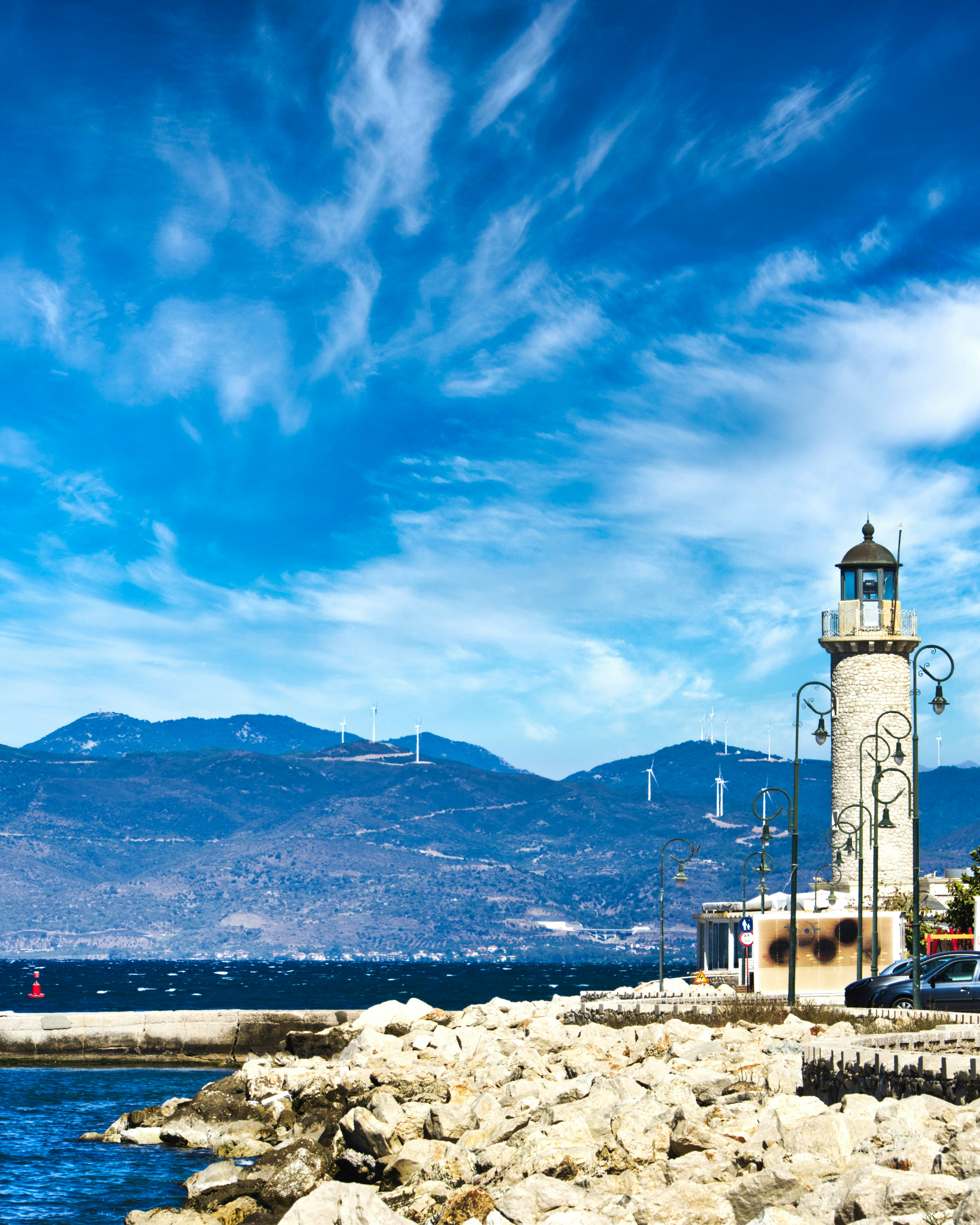 a lighthouse on a rocky shore with mountains in the background
