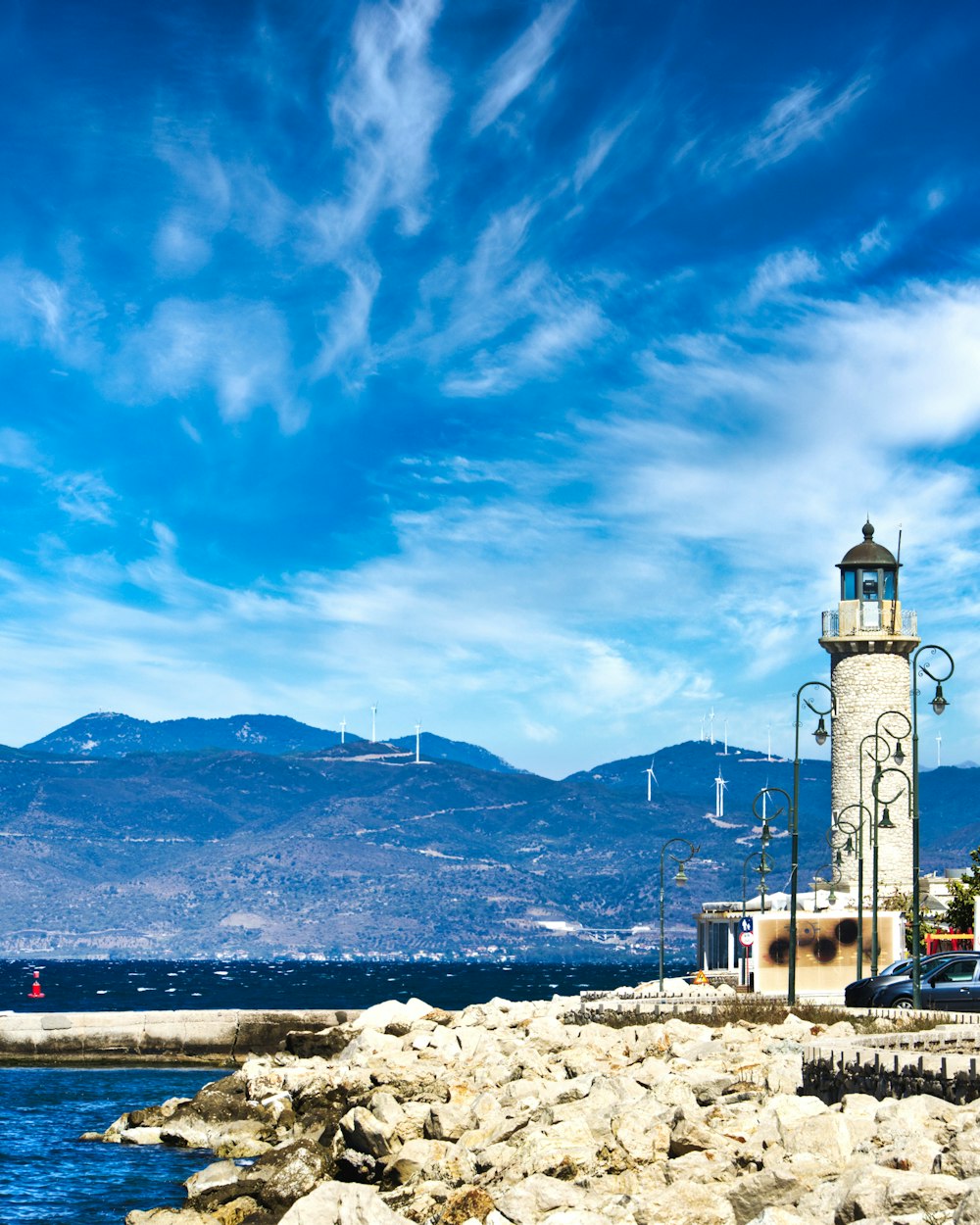 a lighthouse on a rocky shore with mountains in the background