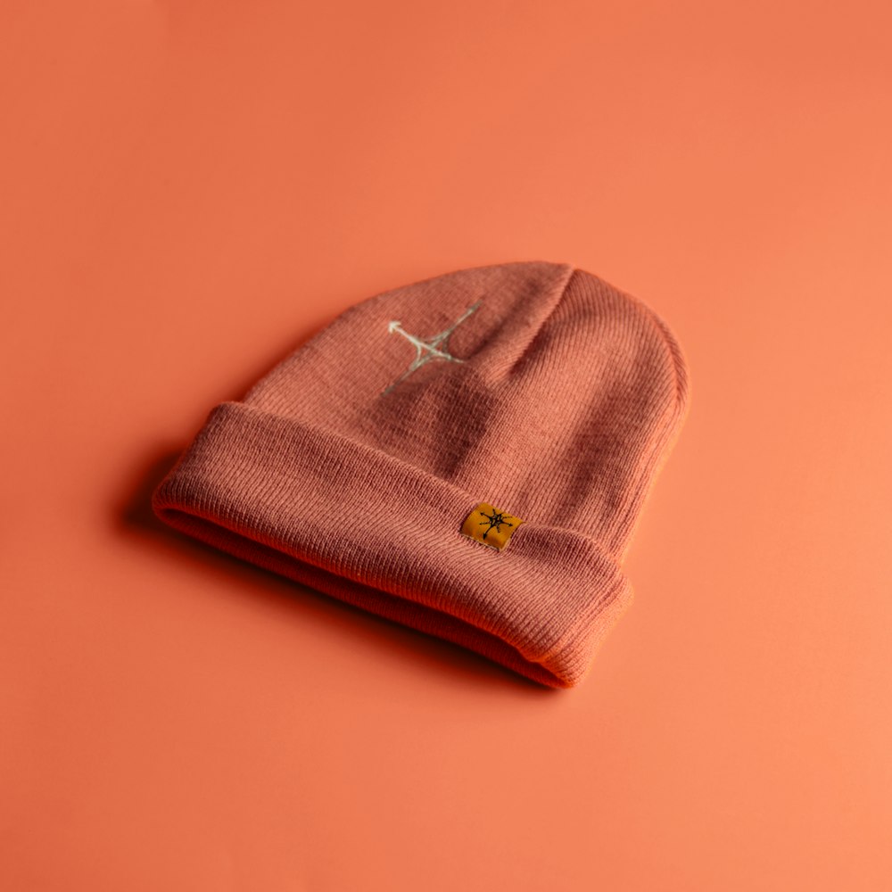 a pink hat with a small bird on it