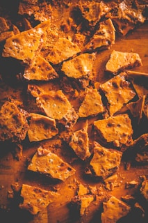 Close-up of homemade toffee pieces wrapped in rustic parchment paper, showcasing their golden, crunchy texture.