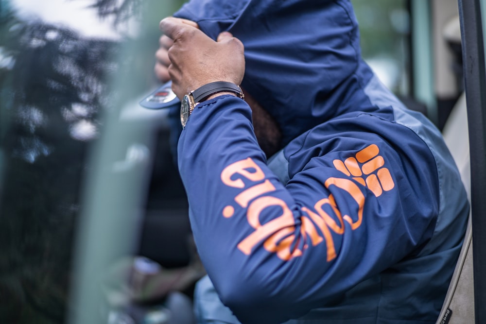 a man in a blue jacket leaning out of a car