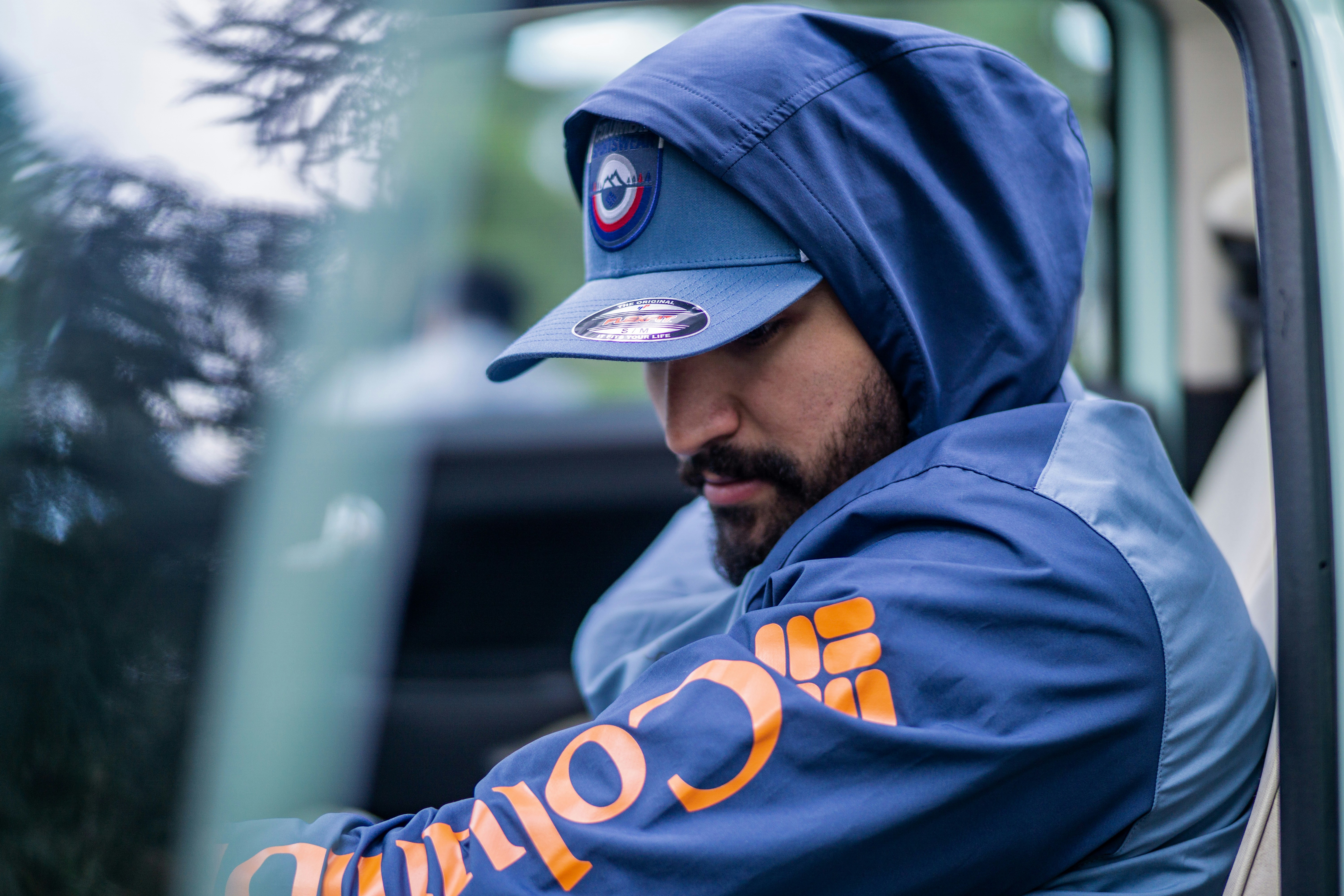 a man in a blue hoodie sitting in a car