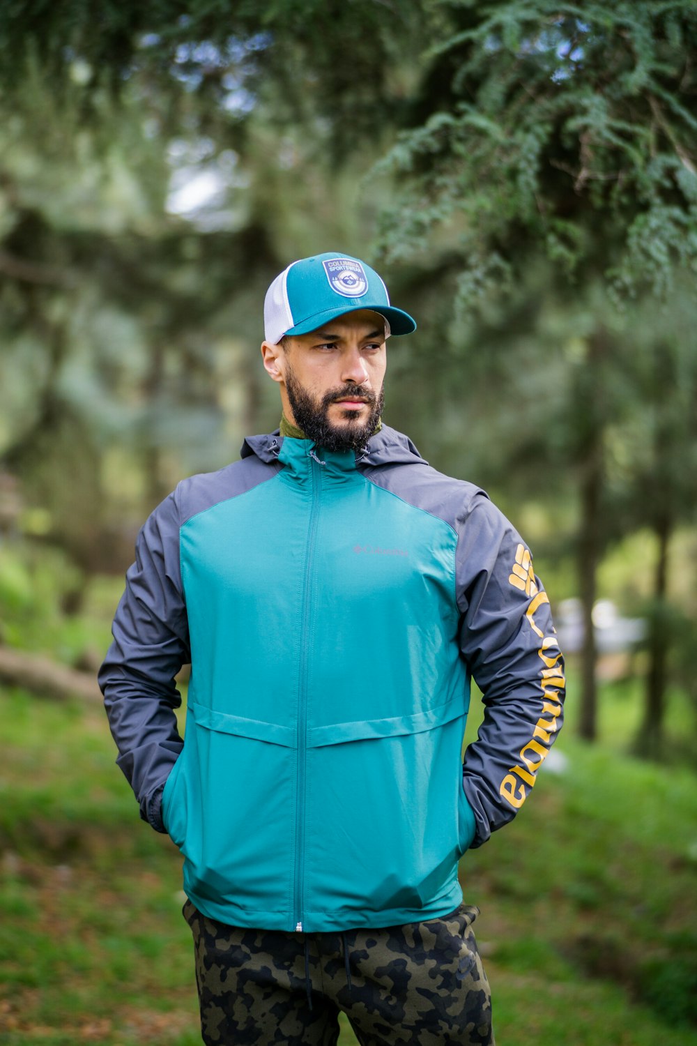 a man standing in the woods wearing a blue jacket