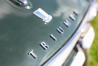 a close up of the letters TRIUMPH on a vintage green British car
