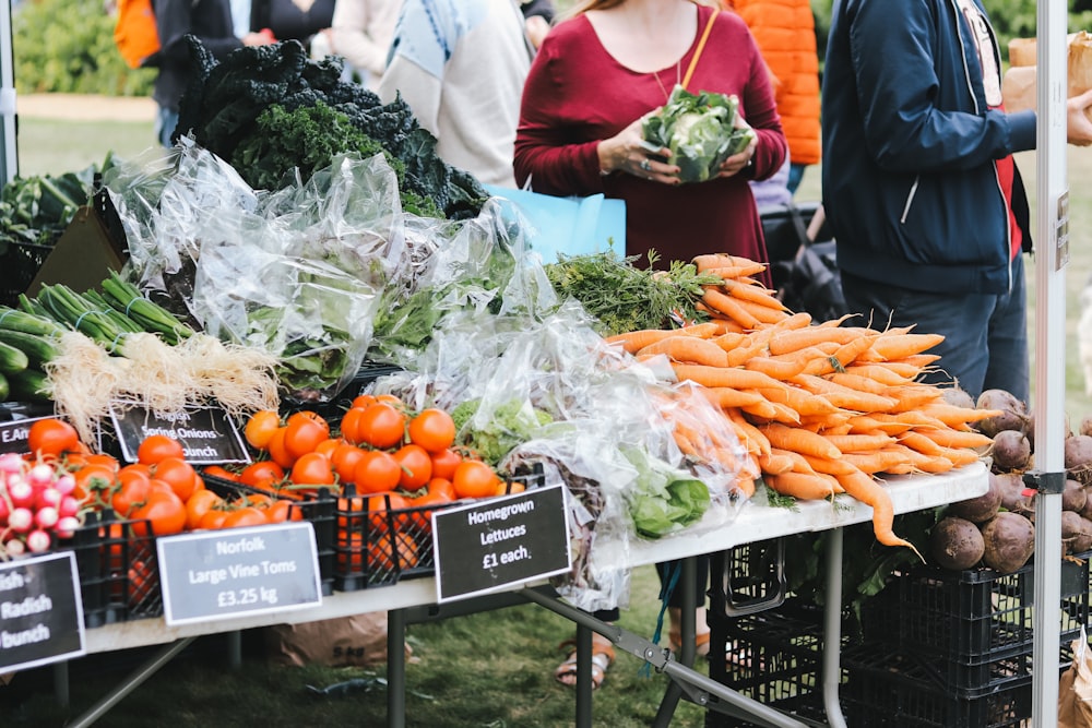 a group of people standing around a table filled with vegetables