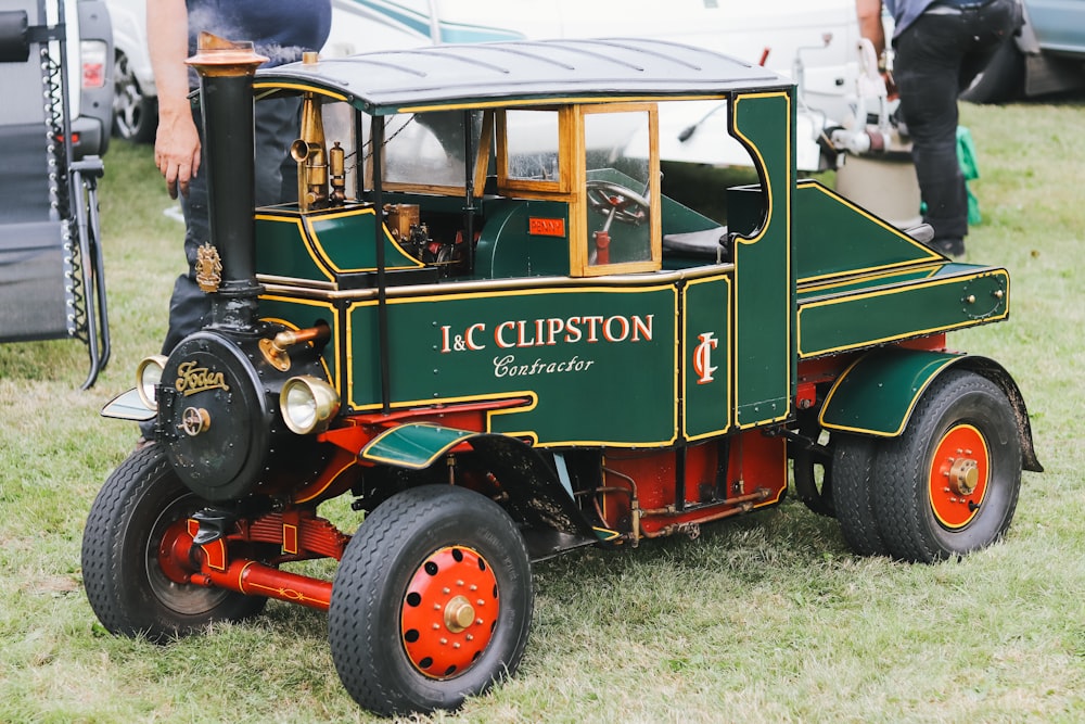 a green and red truck parked on top of a grass covered field