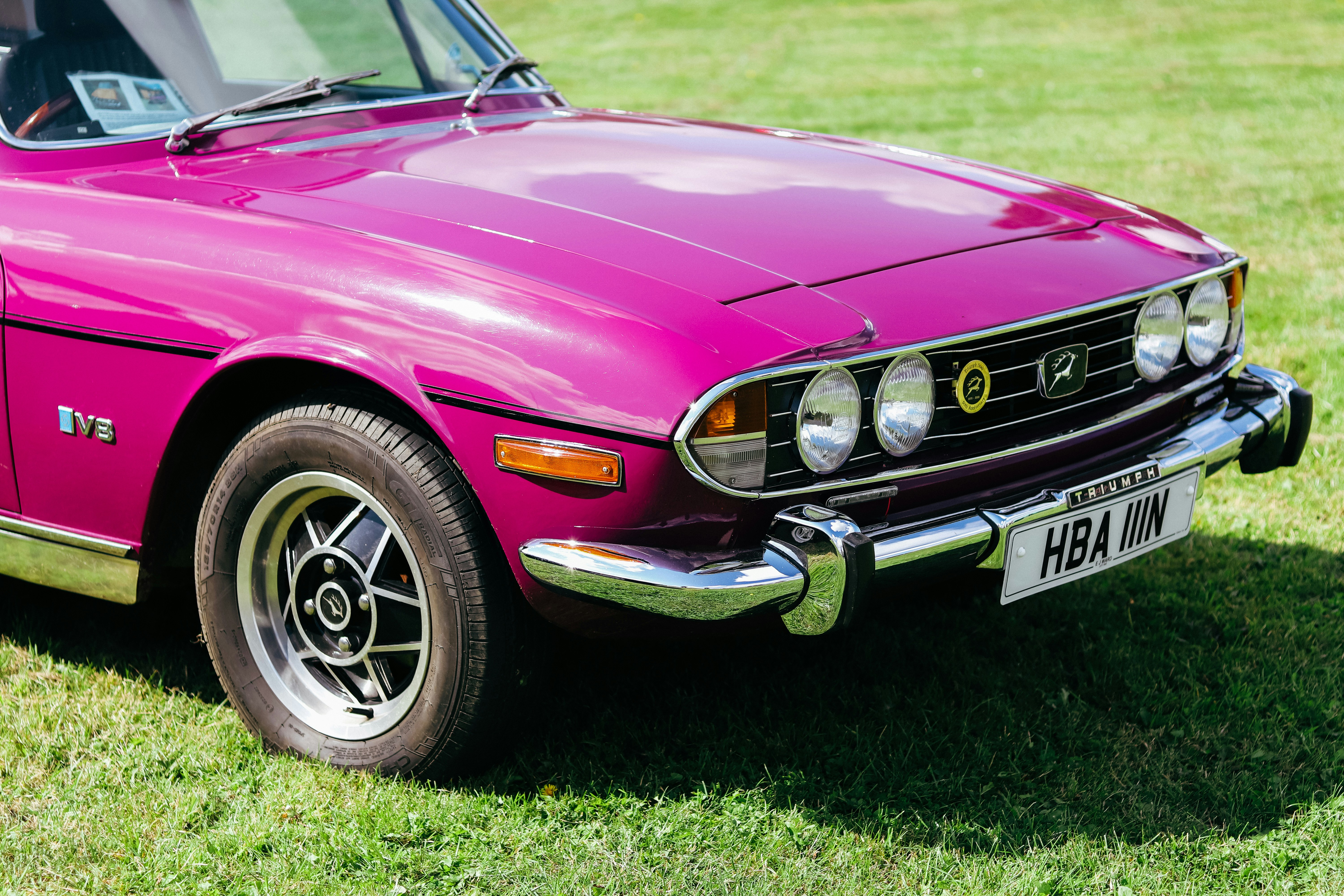 a pink car parked on top of a lush green field