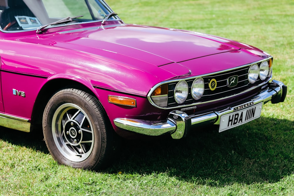 a pink car parked on top of a lush green field