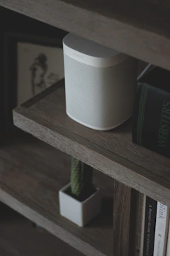 a white speaker sitting on top of a wooden shelf