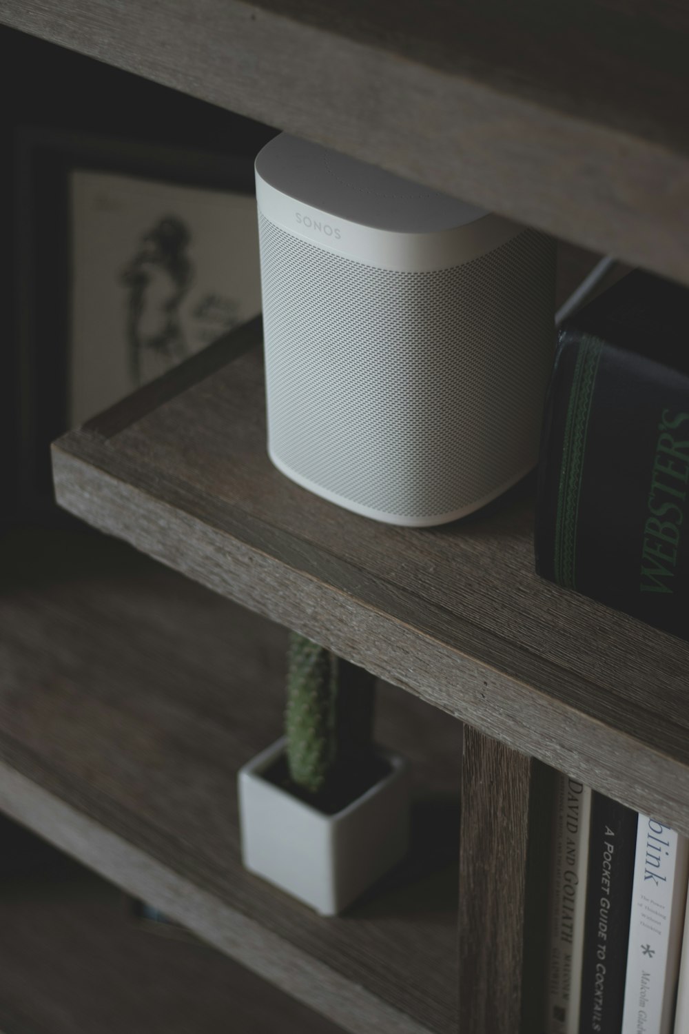 a white speaker sitting on top of a wooden shelf