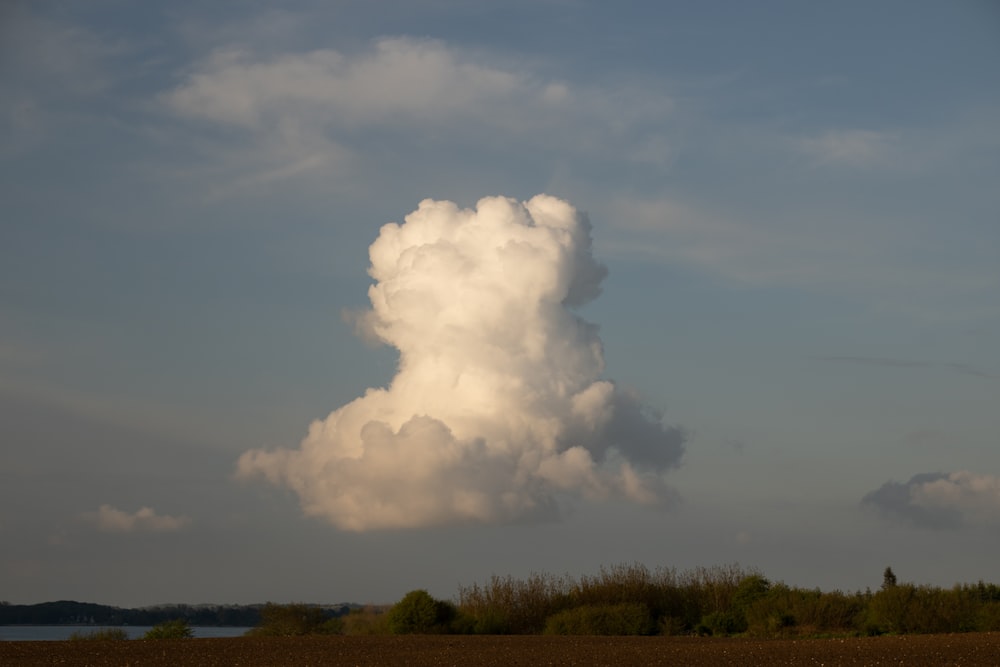 a large cloud is in the sky over a field