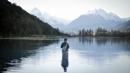 a man standing in the water holding a fish