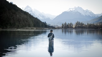 a man standing in the water holding a fish