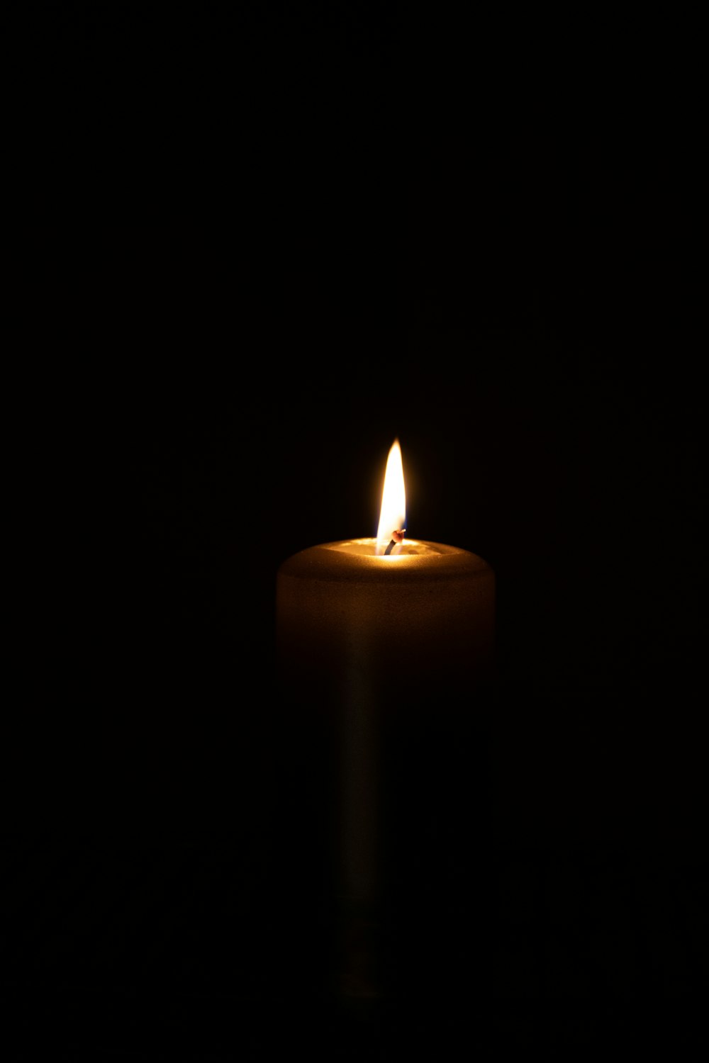 a lit candle in the dark on a black background