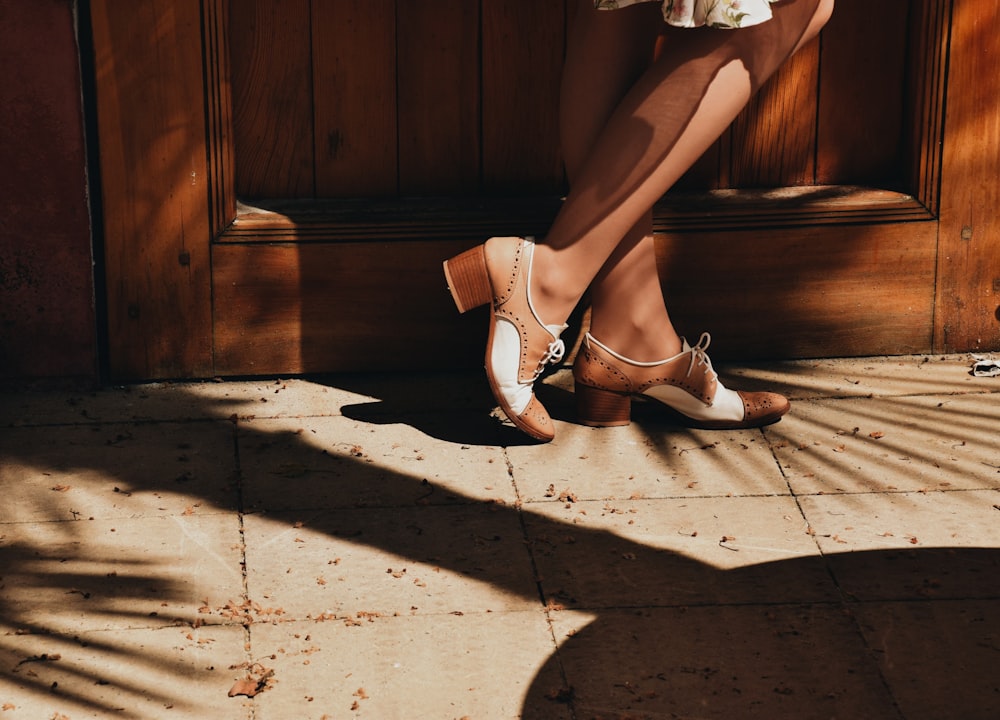 a woman's legs and shoes on a tiled floor