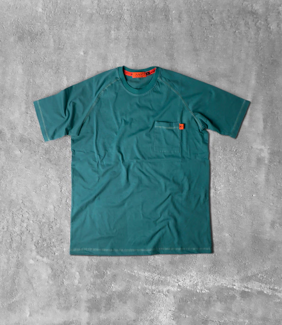 a green t - shirt sitting on a concrete floor