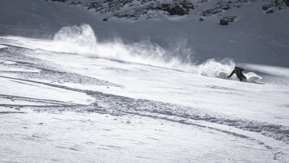 a man riding a snowboard down a snow covered slope