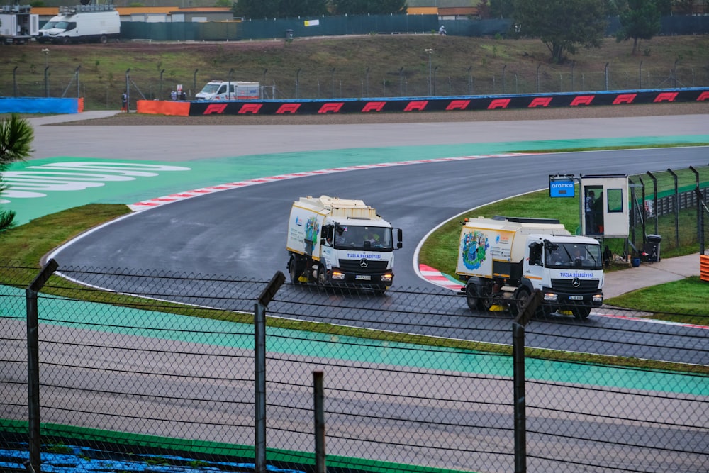 a couple of trucks driving down a race track