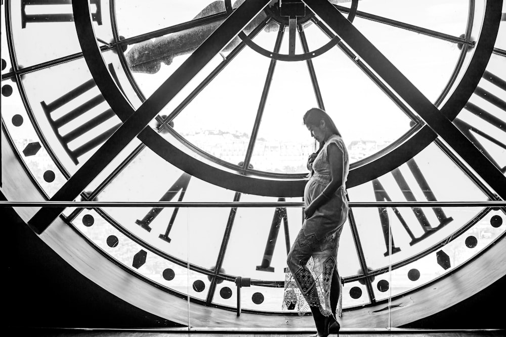 Un hombre parado frente a un gran reloj