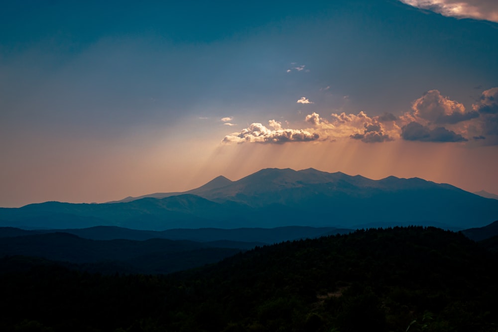 Il sole splende tra le nuvole sopra le montagne