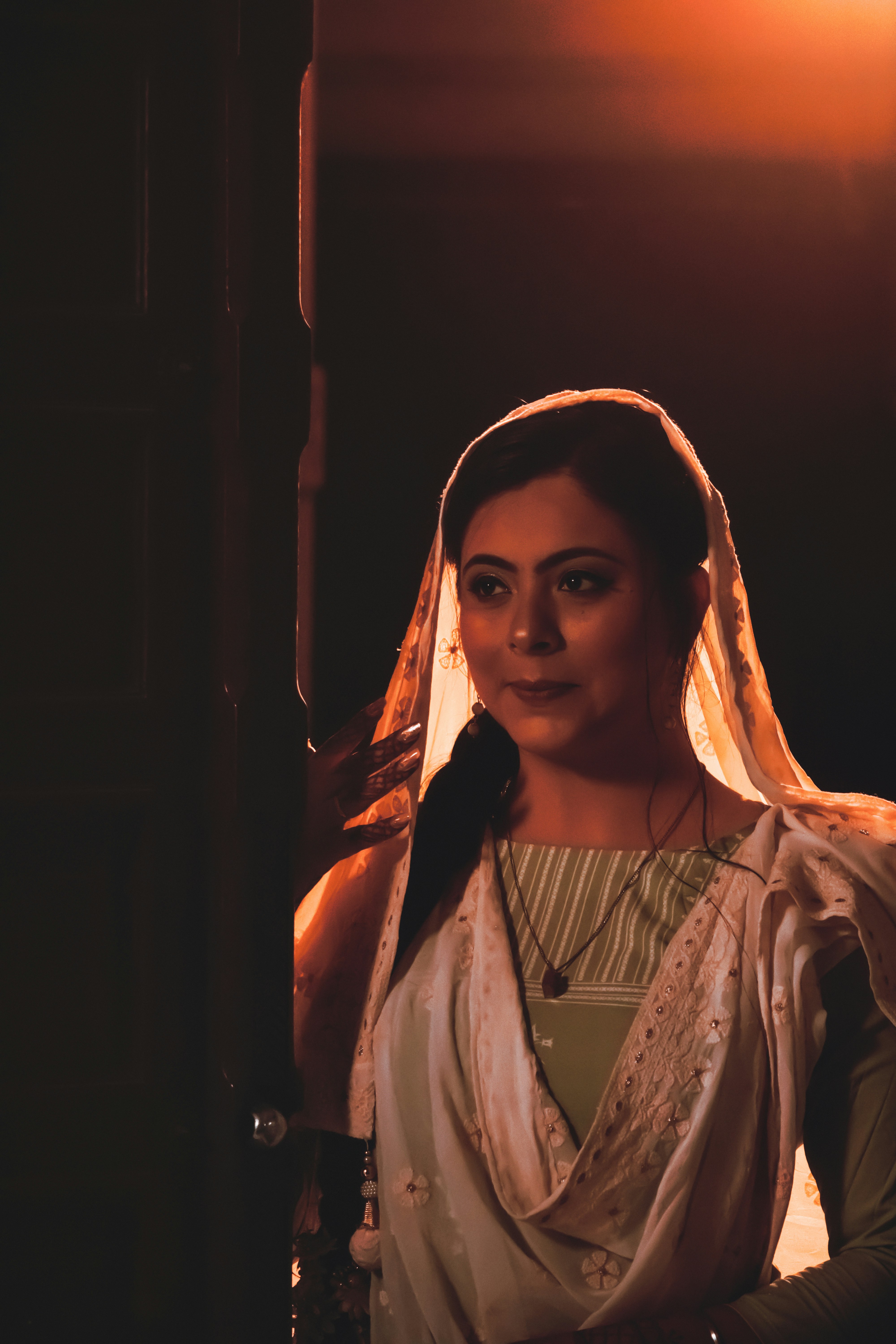 Elegant woman in traditional Indian attire against warm amber background with soft lighting