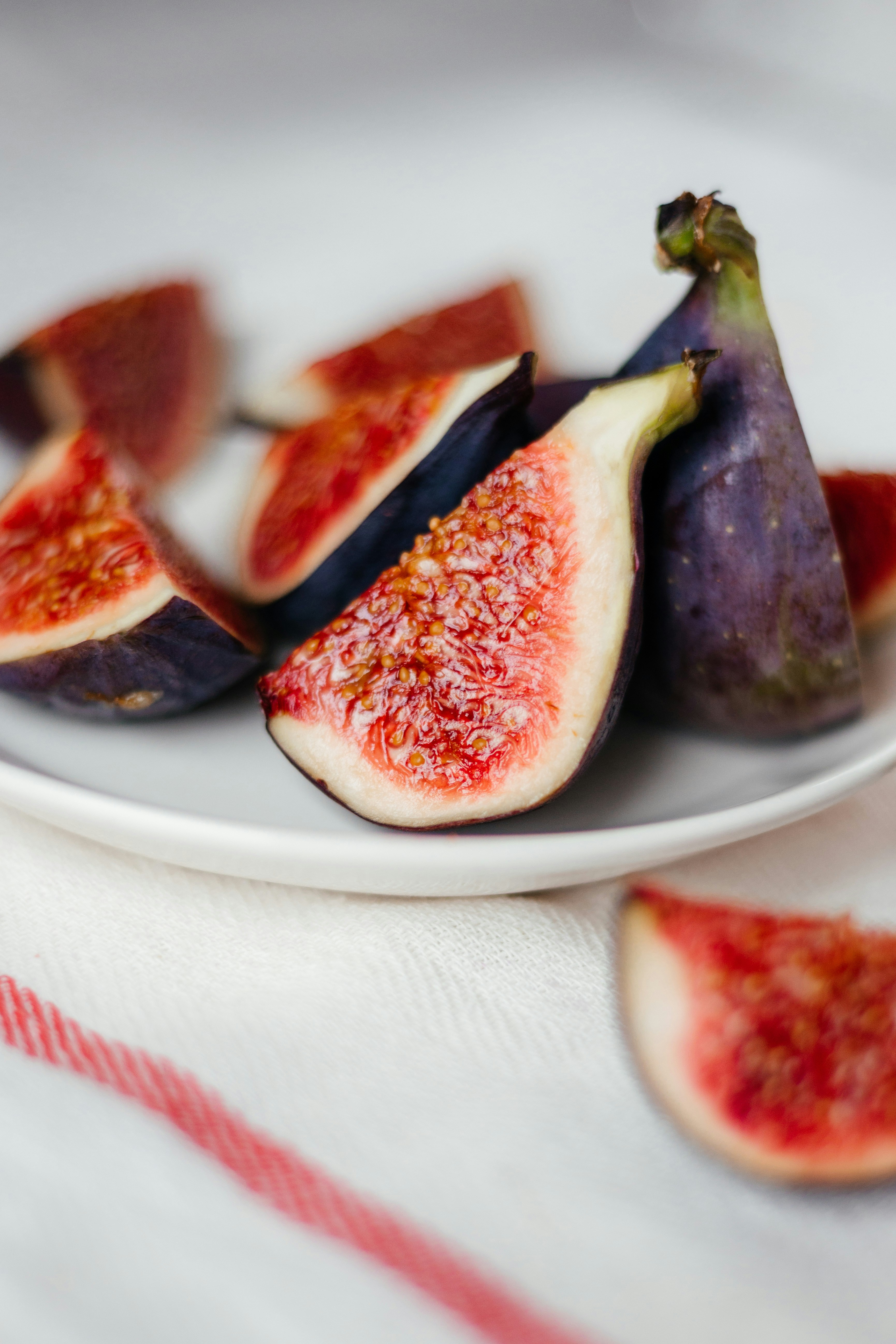 테이블 위에 얇게 썬 무화과를 얹은 흰색 접시