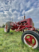 A classic tractor parked beside a field under a big Iowa sky.