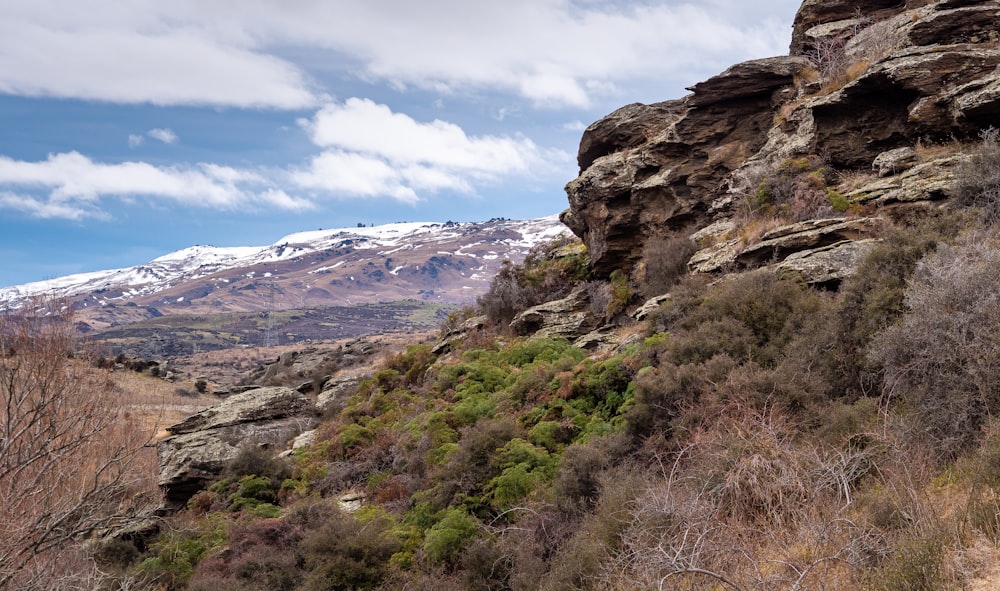 a rocky mountain with a snow covered mountain in the background