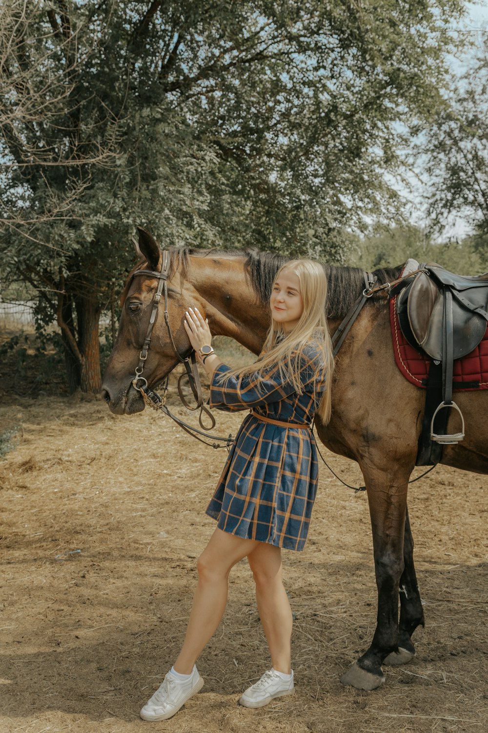 a woman standing next to a brown horse