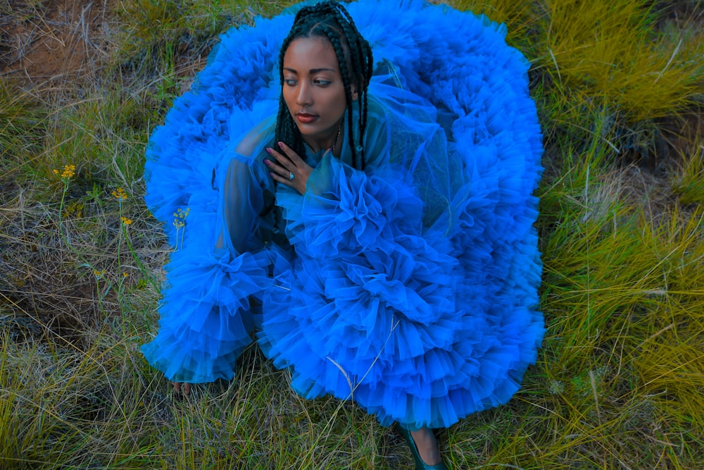 a woman in a blue dress laying on the ground