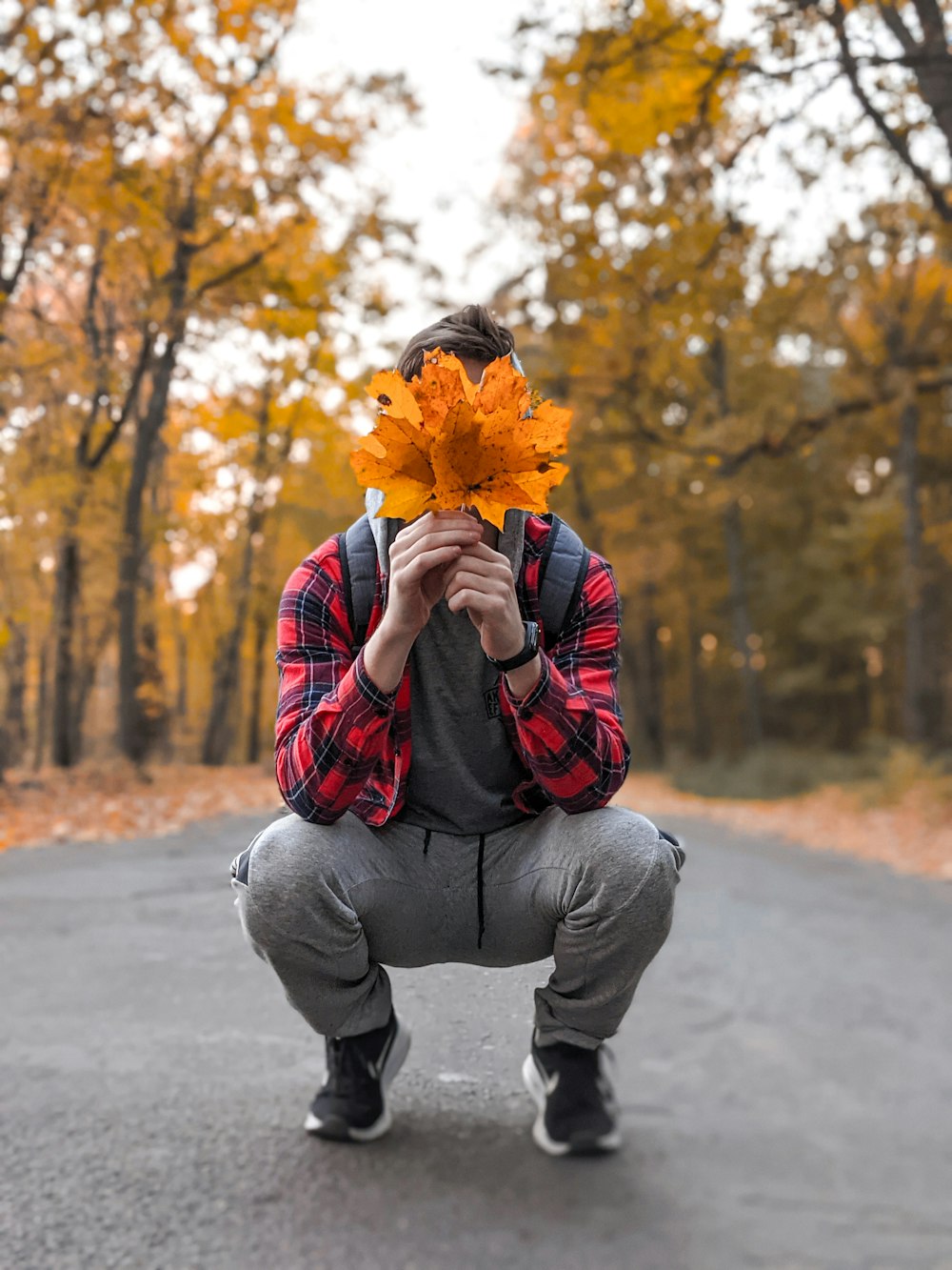 a man kneeling down holding a leaf in front of his face