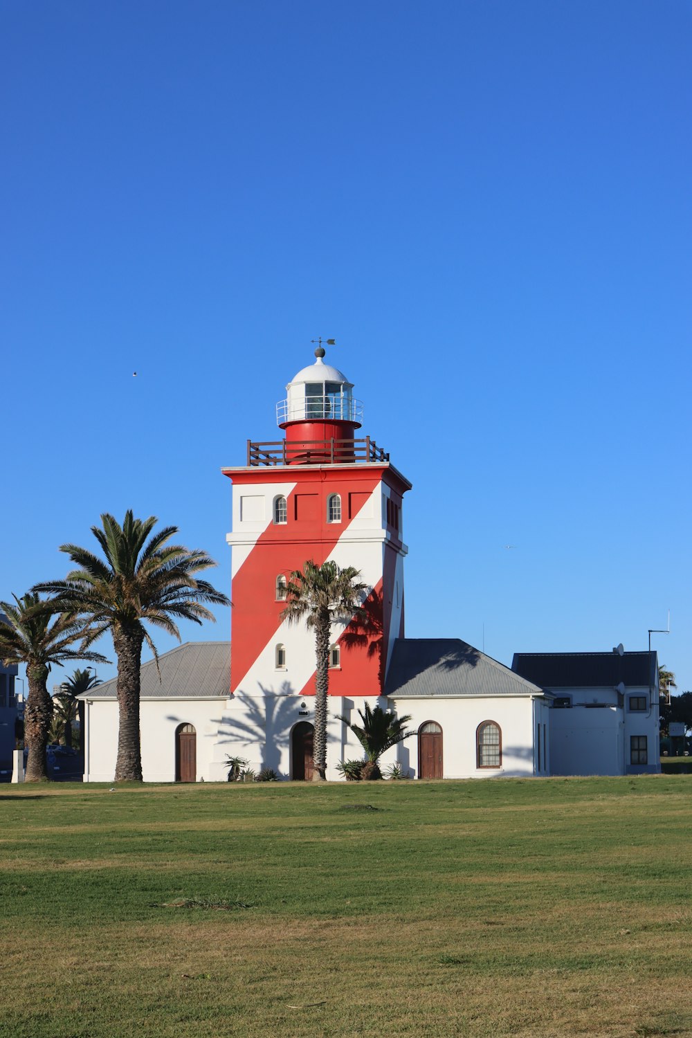 a red and white lighthouse with palm trees in the foreground
