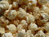 A close-up of freshly popped popcorn, highlighting the texture and details of each kernel. The popcorn is light and fluffy with a slight golden hue, indicating perfect popping.