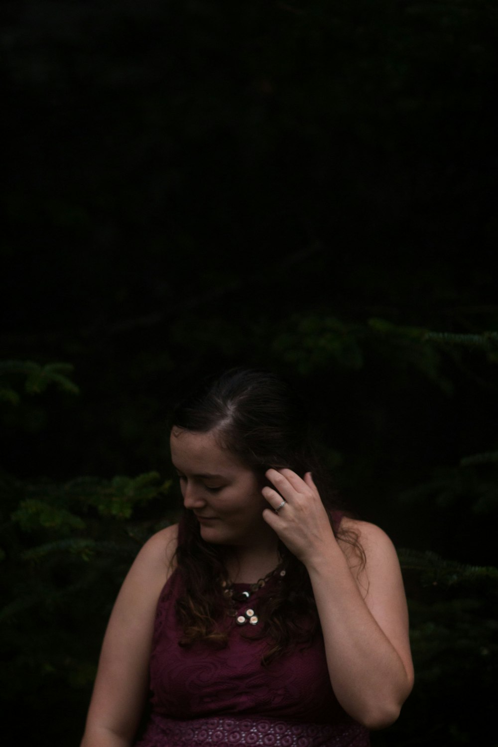 a woman standing in front of a forest holding a cell phone to her ear