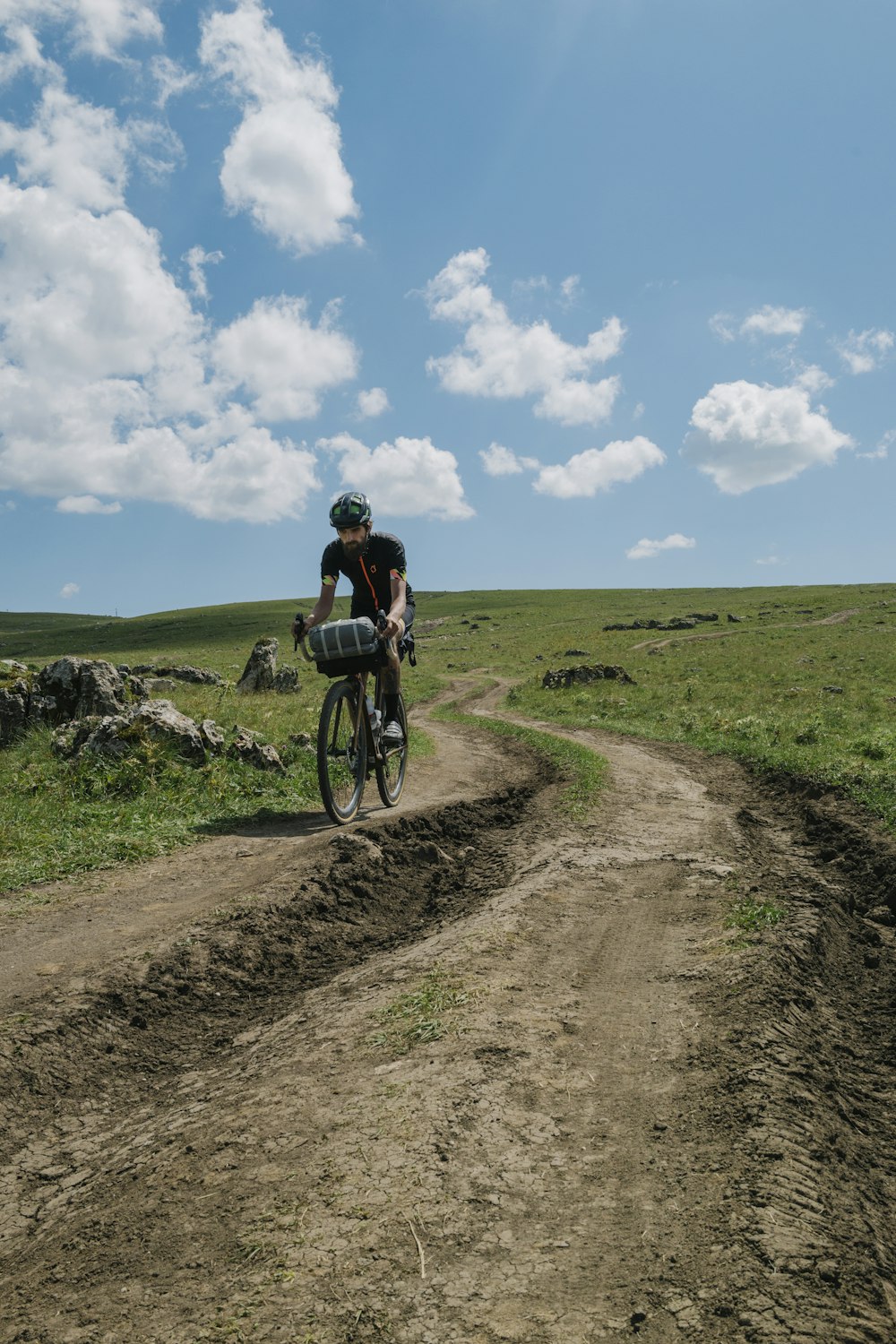 a man riding a bike down a dirt road