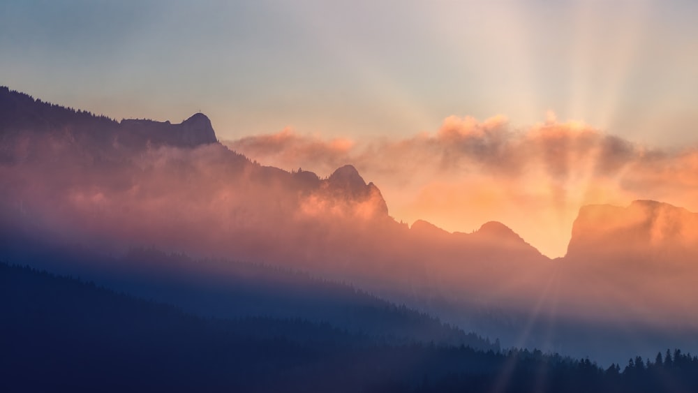 the sun is shining through the clouds over the mountains