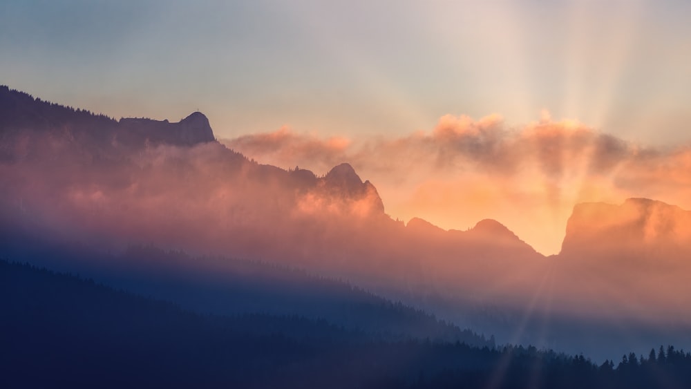El sol brilla a través de las nubes sobre las montañas