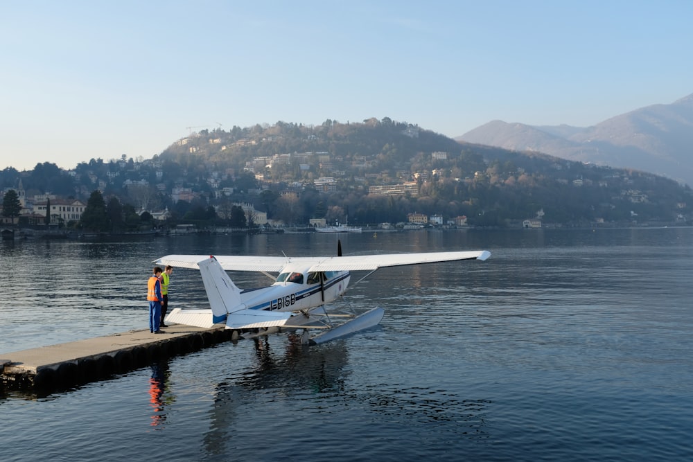 a man standing next to a small plane on a body of water