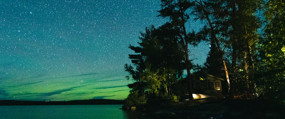 a green and blue sky filled with stars above a body of water
