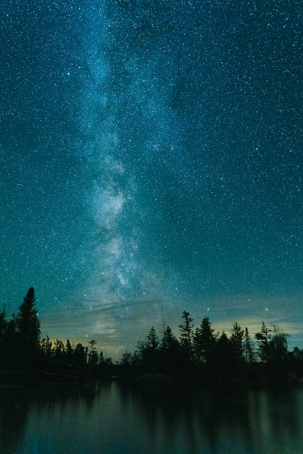 the night sky is filled with stars above a lake