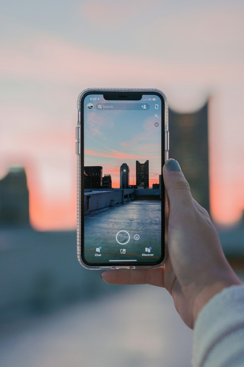 a person holding up a cell phone with a sunset in the background