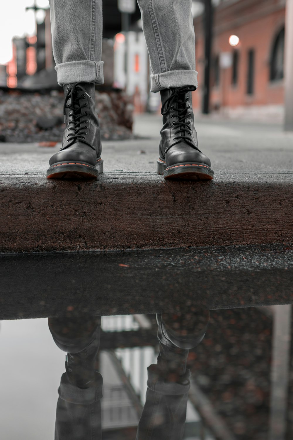 a person standing on a sidewalk next to a puddle