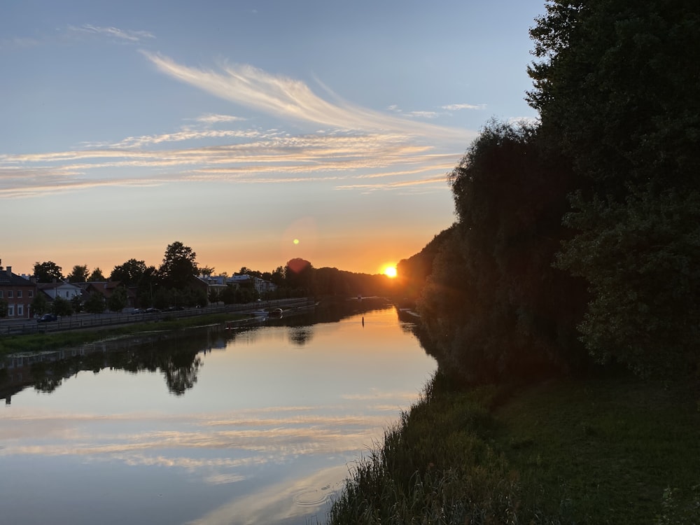 the sun is setting over the water of a river