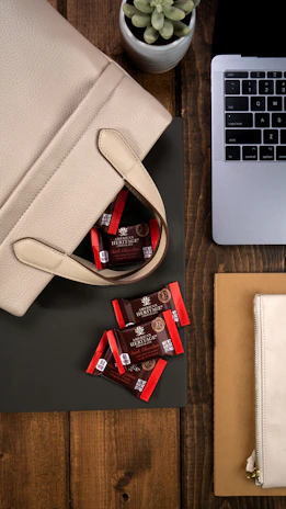 An overhead view of a workspace with Urbancarry bags, leather swatches, and design sketches.